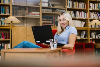 Frau mit Laptop in Bibliothek